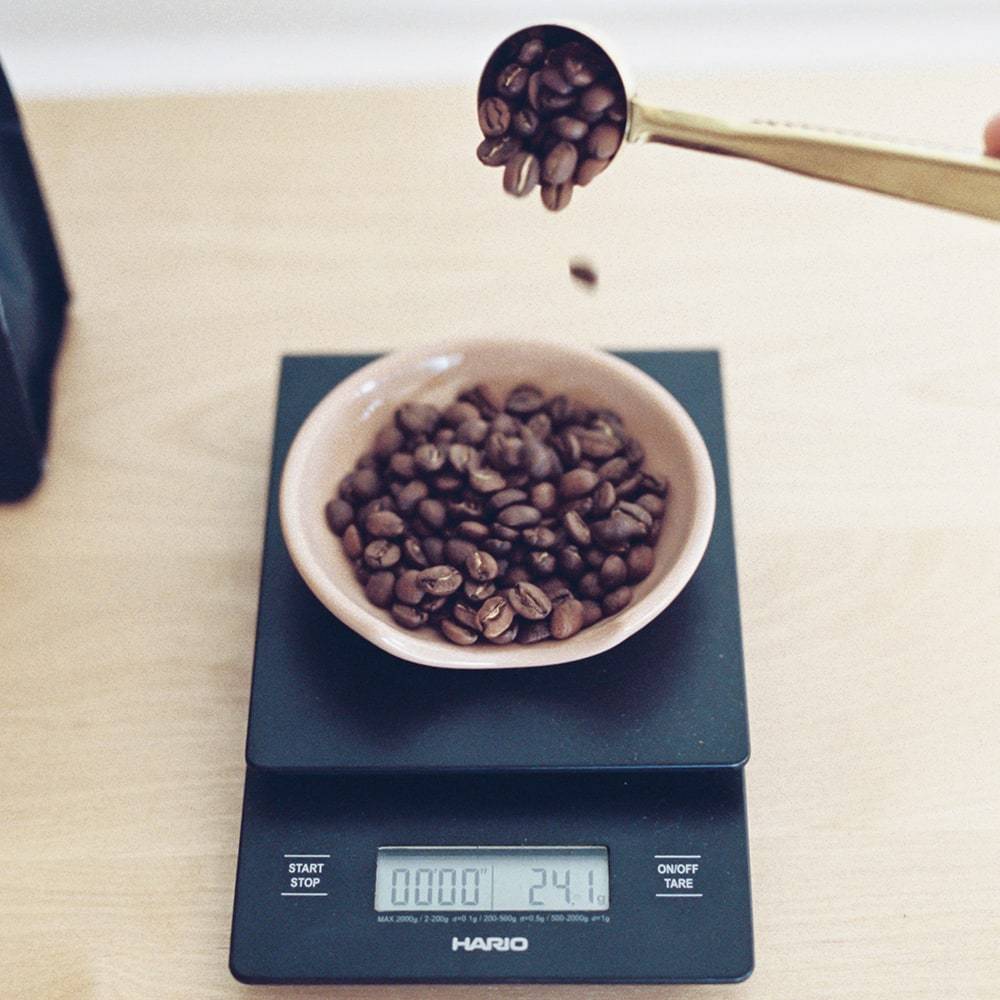 Coffee beans being poured into a bowl on a digital scale