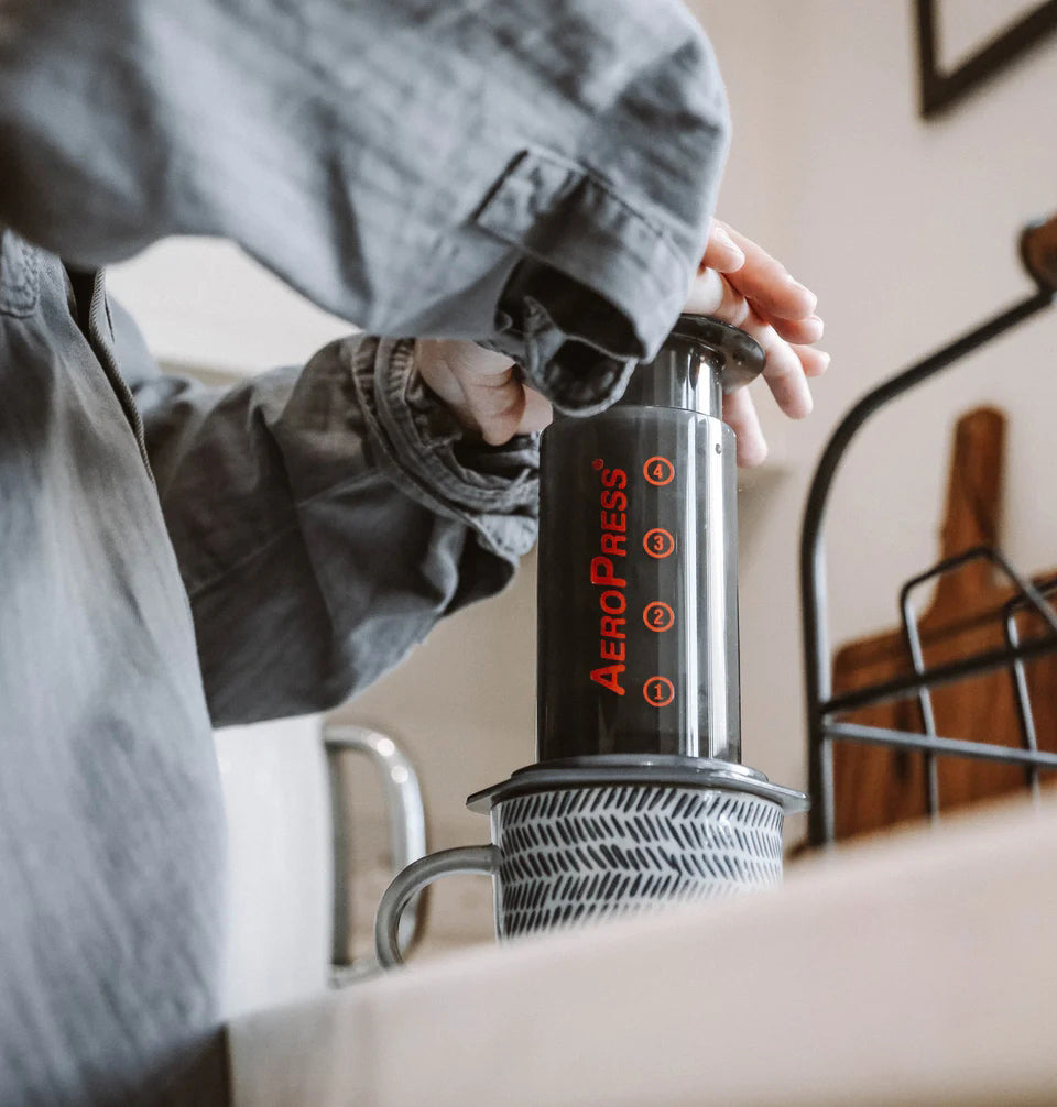 Person using an Aeropress coffee maker with a blurred background