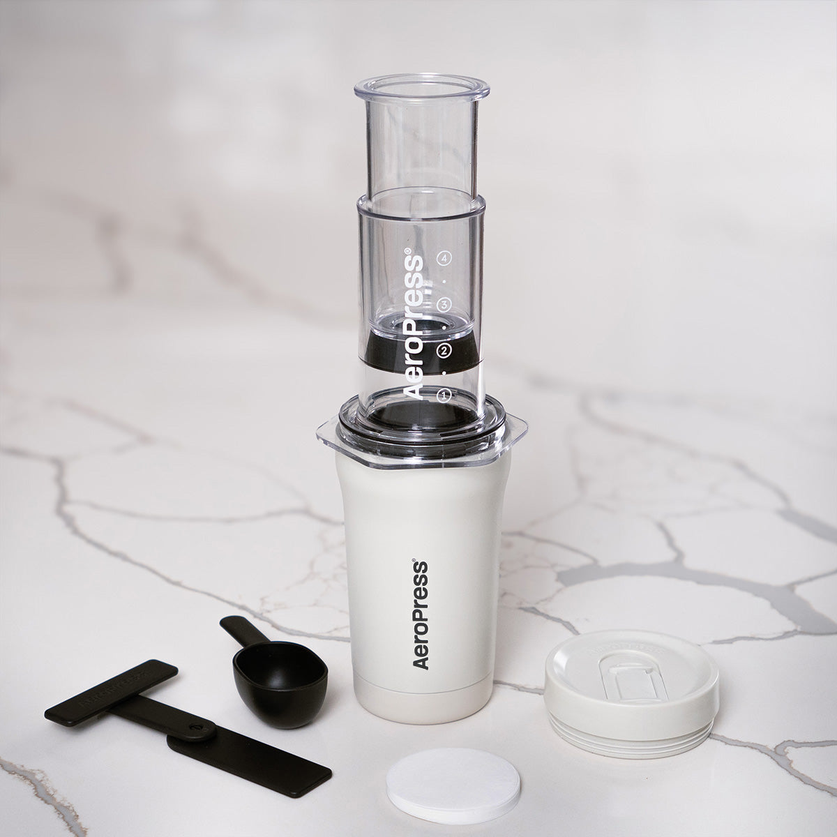 Aeropress coffee maker with components on a marble surface