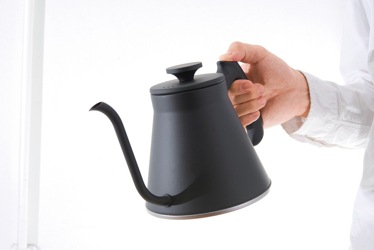 Person holding a black kettle against a white background